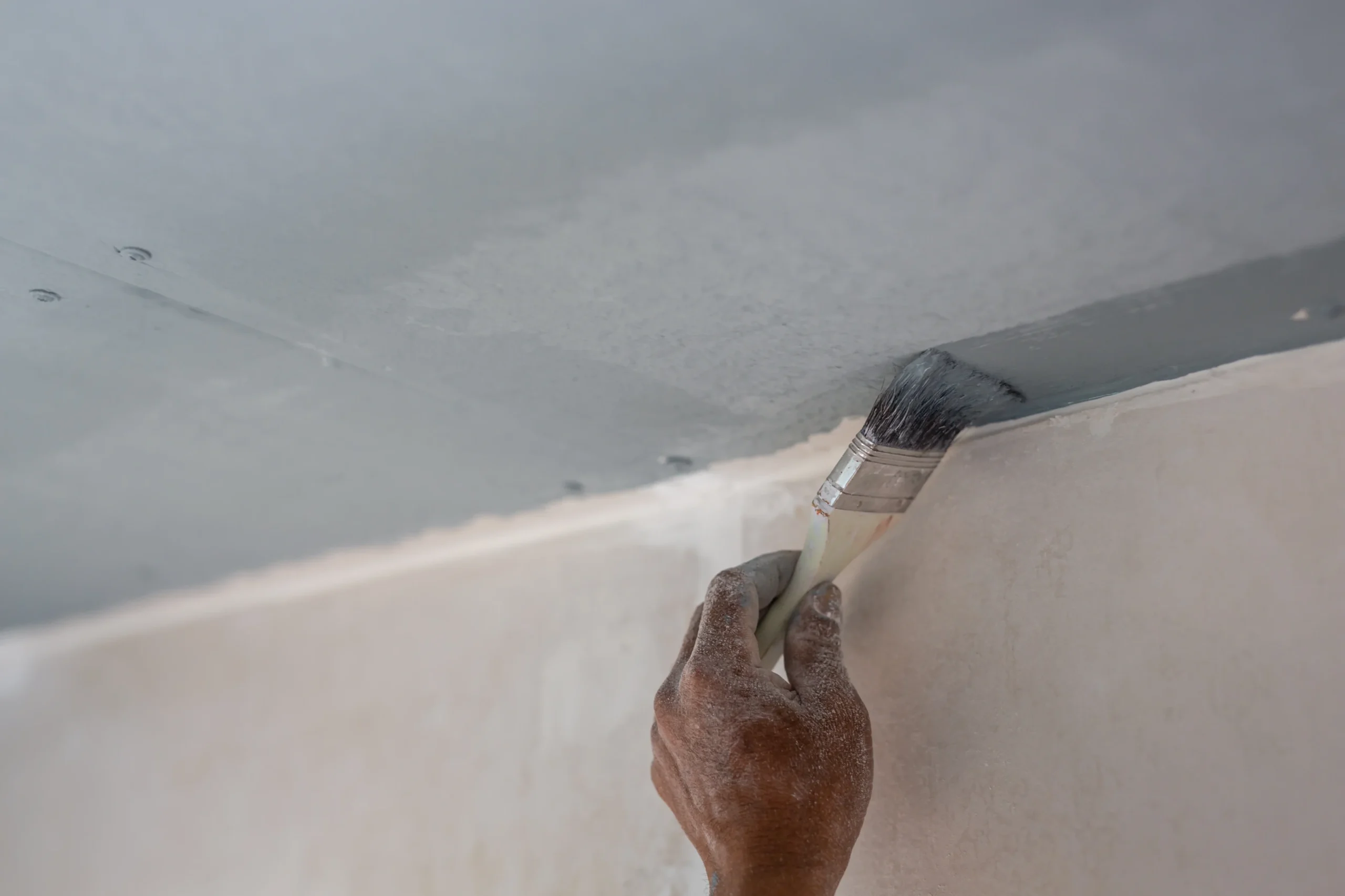 Maler streicht die Wand einer Wohnung – Malerarbeiten Messie-Wohnung